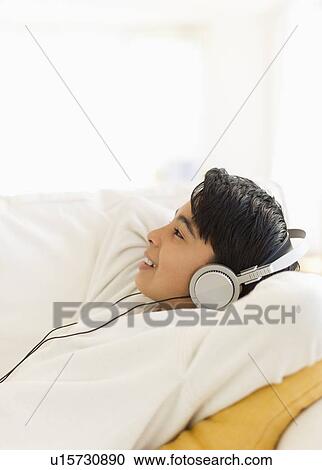 Boy (12-13) listening music on sofa View Large Photo Image Stock Image - Boy (12-13) listening music on sofa. Fotosearch