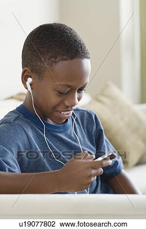 Stock Image - Boy (12-13) listening to music on mp3 player. Fotosearch
