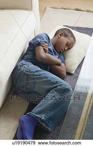 Stock Photo - Boy (12-13) sleeping on carpet. Fotosearch