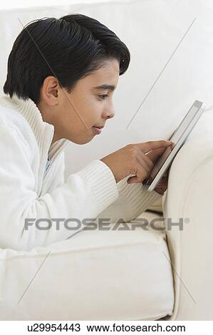 Boy (12-13) using digital tablet on sofa View Large Photo Image Stock Image - Boy (12-13) using digital tablet on sofa. Fotosearch