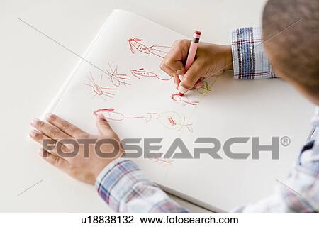 Stock Image - Boy (6-7) drawing in classroom. Fotosearch