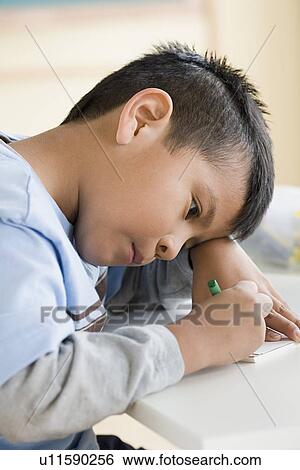 Stock Photograph - Boy (6-7) drawing in classroom. Fotosearch