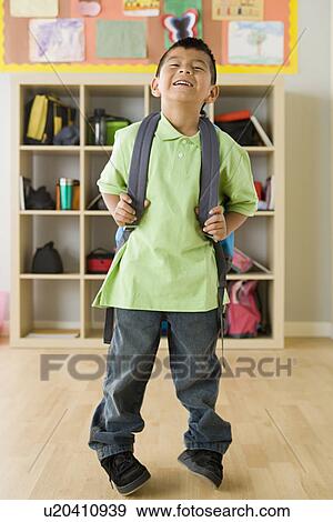 Boy (6-7) holding backpack and laughing View Large Photo Image Stock Photo - Boy (6-7) holding backpack and laughing. Fotosearch