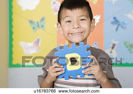 Boy (6-7) holding D letter in classroom View Large Photo Image Stock Photograph - Boy (6-7) holding D letter in classroom. Fotosearch