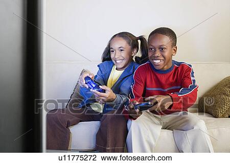 Stock Image - Brother and sister (10-13) playing video game. Fotosearch