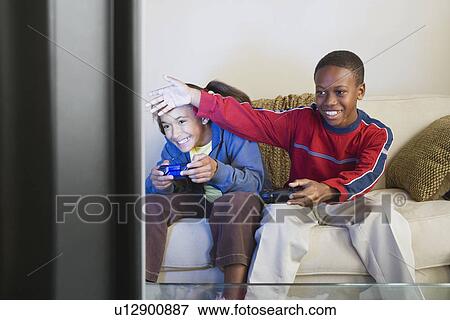 Stock Photo - Brother and sister (10-13) playing video game. Fotosearch