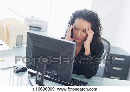Business woman using computer holding head in hands View Large Photo Image Stock Photo - Business woman using computer holding head in hands. Fotosearch