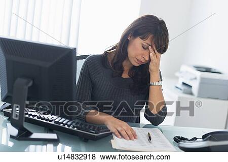 Stock Photo - Business woman using computer, looking tired. Fotosearch