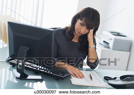 Stock Photo - Business woman using computer, looking tired. Fotosearch