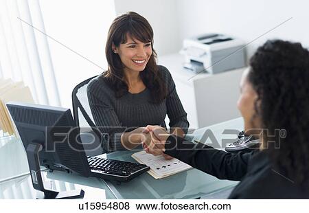 Stock Photo - Business women shaking hands in office. Fotosearch