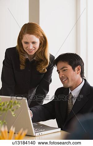 Stock Image - Businessman and businesswoman using laptop. Fotosearch