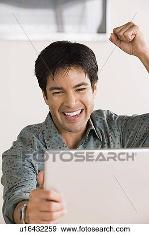 Businessman celebrating in front of laptop View Large Photo Image Stock Photo - Businessman celebrating in front of laptop. Fotosearch