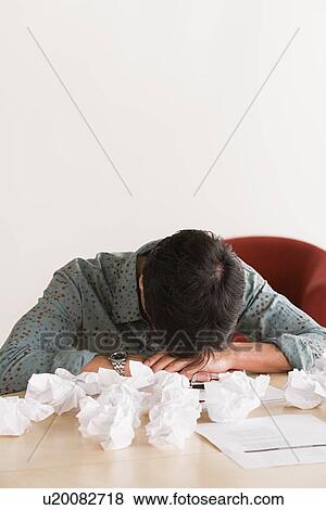 Stock Photo - Businessman sleeping at desk with crumpled paper balls. Fotosearch