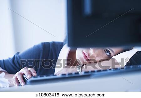 Stock Photography - Businesswoman looking tired in front of computer. Fotosearch
