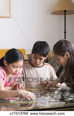 Stock Photo - Children (8-9, 10-11) playing with puzzle. Fotosearch