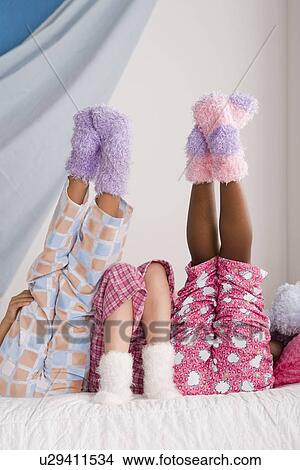 Close op of legs of three girls (10-11) lying on bed with feet up View Large Photo Image Picture - Close op of legs of three girls (10-11) lying on bed with feet up. Fotosearch