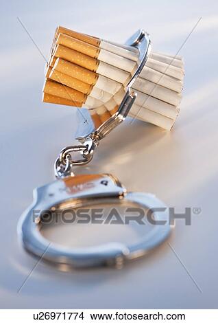 Picture - Close up of bunch of cigarettes locked in handcuffs. Fotosearch