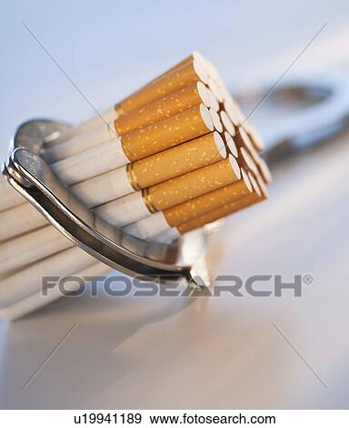 Stock Photo - Close up of bunch of cigarettes locked in handcuffs. Fotosearch
