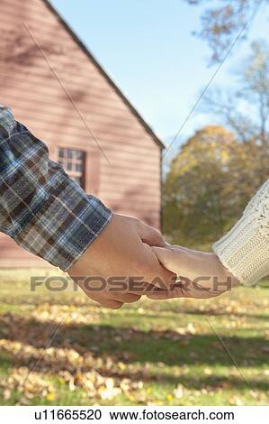 Close-up of couple holding hands in front of cottage house View Large Photo Image Stock Image - Close-up of couple holding hands in front of cottage house. Fotosearch