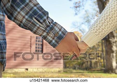 Close-up of couple holding hands in front of cottage house View Large Photo Image Stock Photo - Close-up of couple holding hands in front of cottage house. Fotosearch