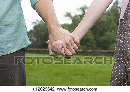 Stock Image - Close-up of couple holding hands. Fotosearch