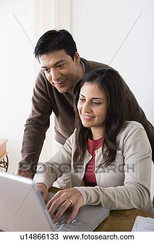 Stock Image - Close up of couple using laptop. Fotosearch