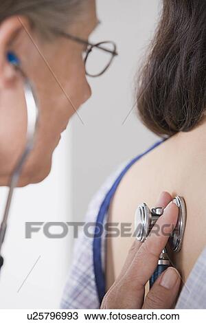 Stock Image - Close up of female doctor examining patient with stethoscope. Fotosearch