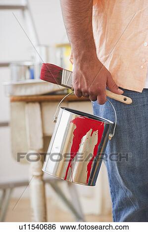 Stock Photograph - Close up of man's hand holding pain brush and paint can. Fotosearch