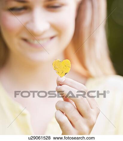 Stock Photo - Close up woman holding heart shaped leaf. Fotosearch