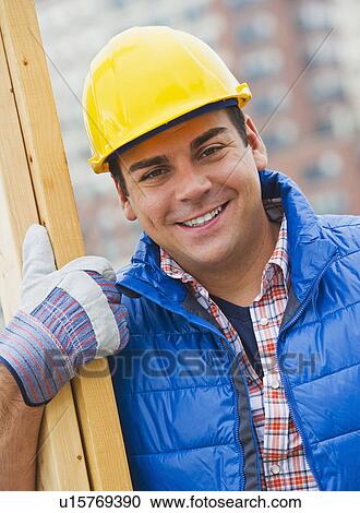 Construction worker carrying planks on construction site View Large Photo Image Stock Image - Construction worker carrying planks on construction site. Fotosearch