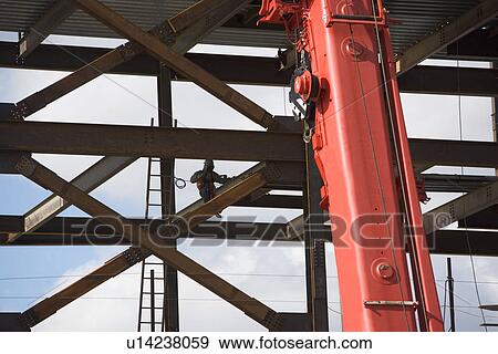 Construction worker working on unfinished structure, red crane in foreground View Large Photo Image Stock Photo - Construction worker working on unfinished structure, red crane in foreground. Fotosearch