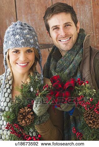 Stock Image - Couple holding christmas wreath. Fotosearch
