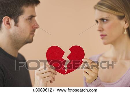 Couple holding red broken paper heart View Large Photo Image Stock Photo - Couple holding red broken paper heart. Fotosearch