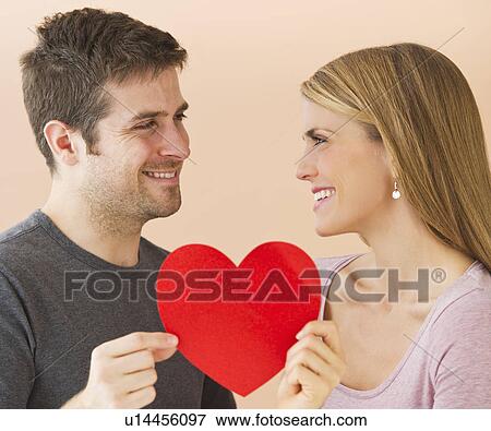 Couple holding red paper heart View Large Photo Image Stock Photo - Couple holding red paper heart. Fotosearch