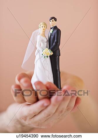 Stock Image - Couple holding small wedding figurine. Fotosearch