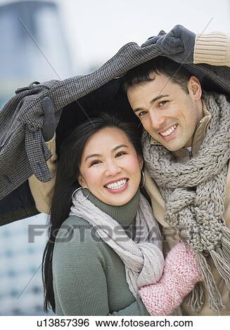 Stock Photograph - Couple walking with jacket over heads. Fotosearch