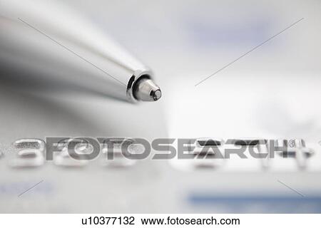 Stock Image - Detail of credit card with ballpoint pen, studio shot. Fotosearch