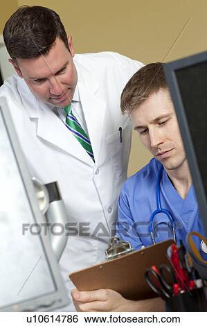 Stock Photograph - Doctor and surgeon reading medical record in doctor's office. Fotosearch