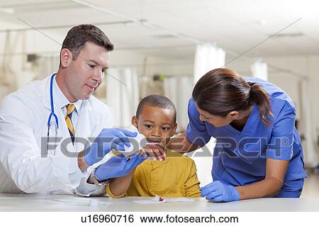 Stock Photograph - Doctors applying bandage on boy's (4-5) hand. Fotosearch
