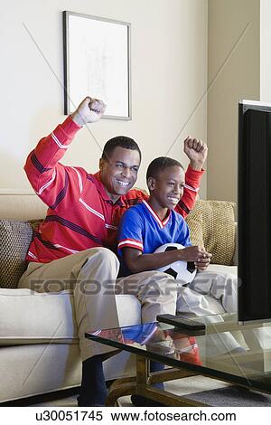Father and Son (12-13) watching sports on tv View Large Photo Image Stock Photography - Father and Son (12-13) watching sports on tv. Fotosearch