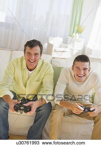 Father and son (16-17) playing video game View Large Photo Image Stock Image - Father and son (16-17) playing video game. Fotosearch