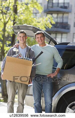 Stock Photograph - Father helping teenage son (16-17) packing to college. Fotosearch