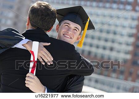 Stock Photo - Father with teenage sun (16-17) at graduation ceremony. Fotosearch