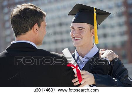 Stock Photo - Father with teenage sun (16-17) at graduation ceremony. Fotosearch