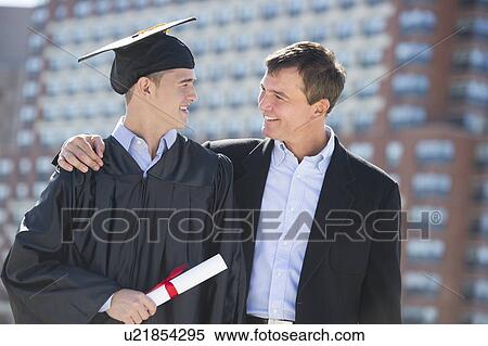 Stock Photography - Father with teenage sun (16-17) at graduation ceremony. Fotosearch