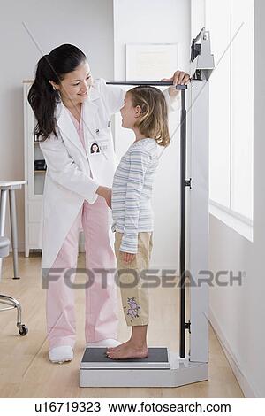 Stock Image - Female doctor measuring girl (4-5). Fotosearch
