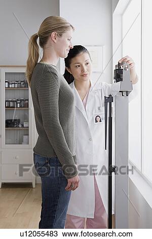Female doctor measuring woman's weight View Large Photo Image Stock Image - Female doctor measuring woman's weight. Fotosearch