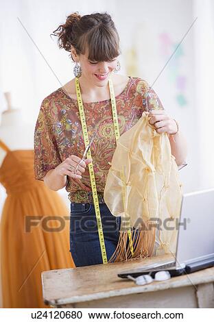 Stock Image - Female fashion designer working in studio. Fotosearch