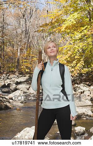 Female hiker standing by stream in forest View Large Photo Image Stock Image - Female hiker standing by stream in forest. Fotosearch
