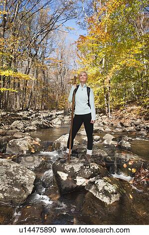 Female hiker standing on rock in stream in forest View Large Photo Image Stock Image - Female hiker standing on rock in stream in forest. Fotosearch